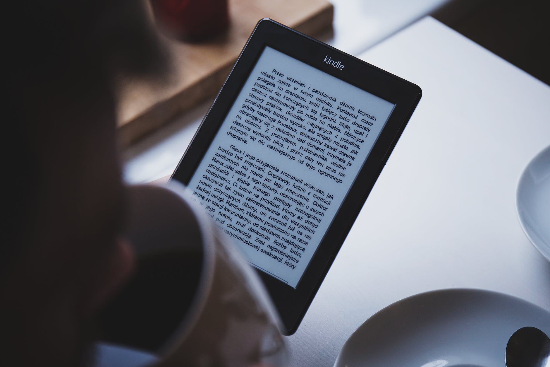 person using e book reader while drinking coffee. Kindle for language learning